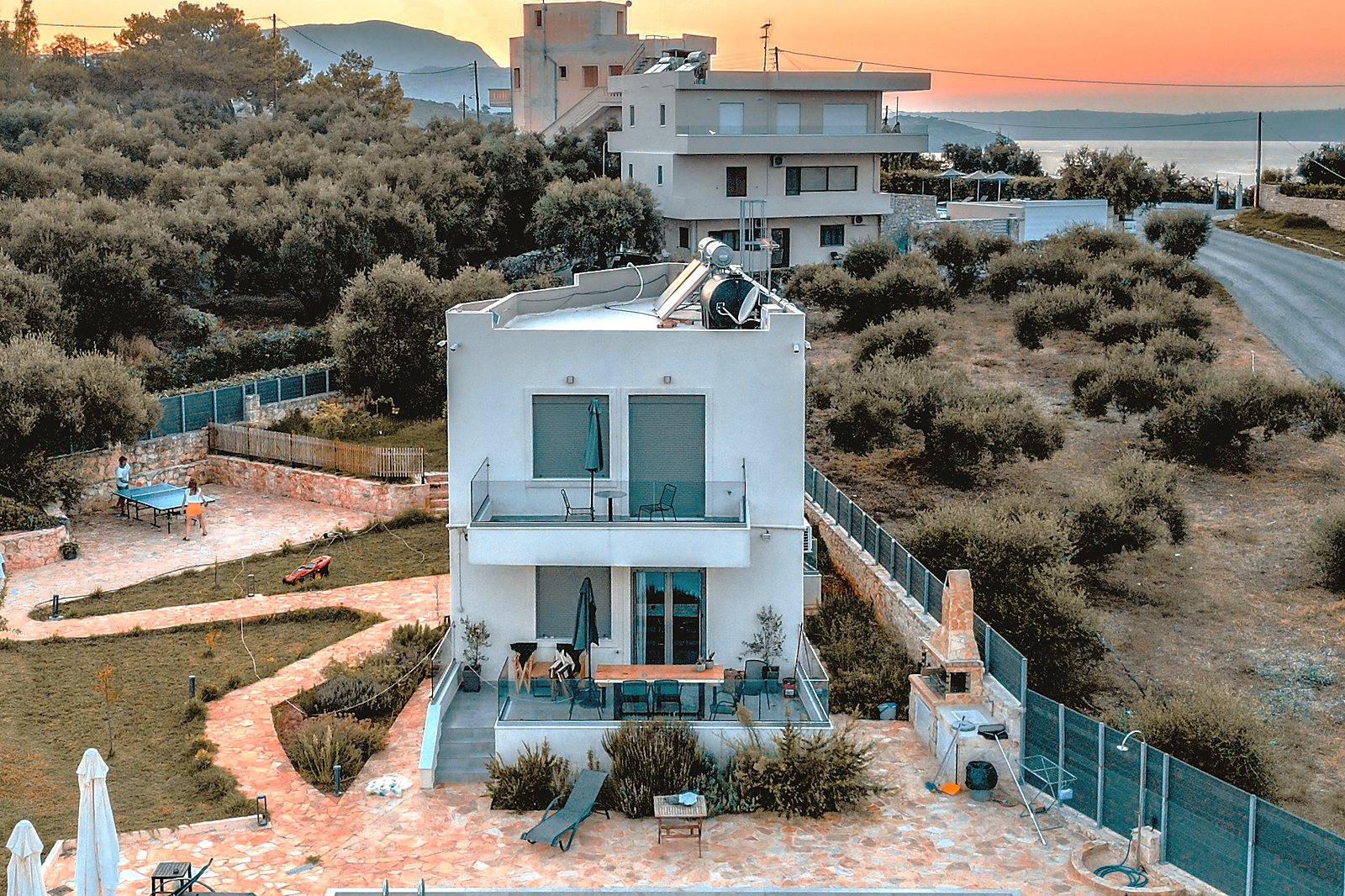 Aerial view of Horizon Villa Almyrida at sunset, set among olive groves with the sea beyond