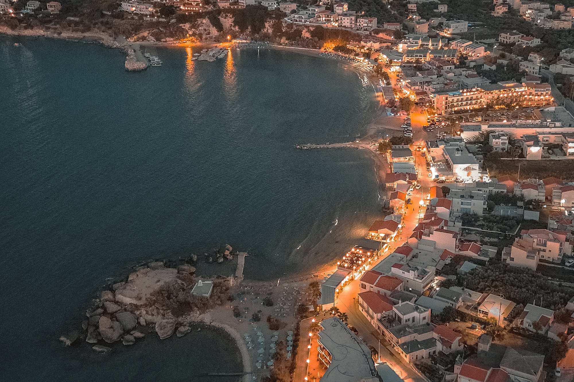 Aerial view of Almyrida bay at dusk, the village lights tracing the shoreline