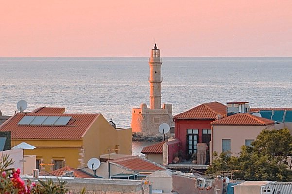An Ottoman minaret rising above the rooftops of Chania Old Town, the sea behind