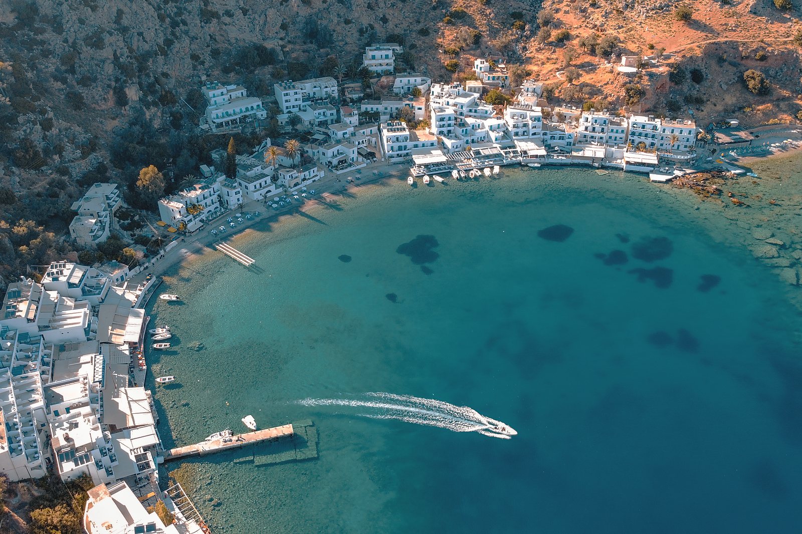 Aerial view of Loutro, the car-free village on the Sfakian coast, with a boat crossing its bay
